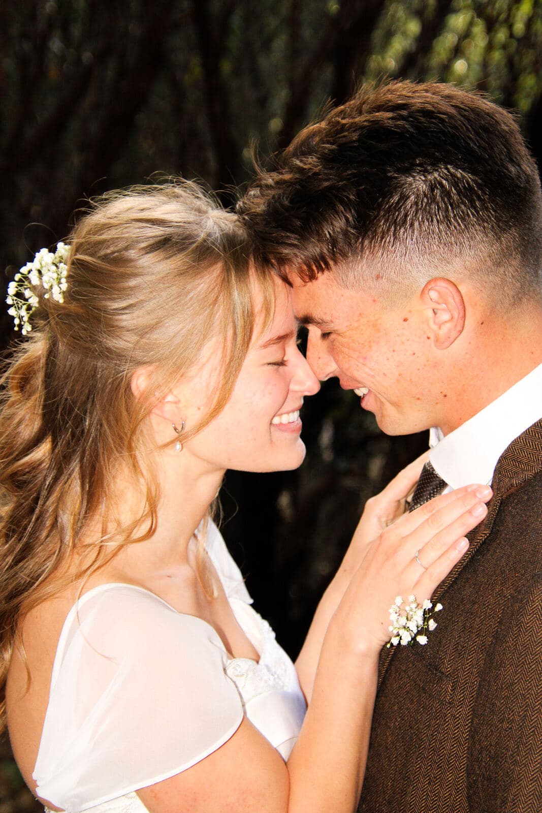 bride and groom touching foreheads and smiling with eyes closed in a close romantic portrait